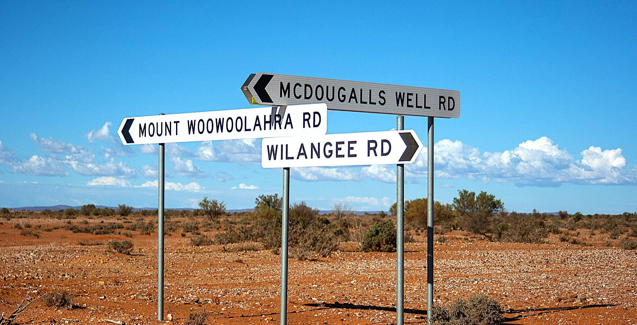 Road signs at the Broughams Gate intersection north of Silverton, NSW, marking how far into the outback the journey goes.